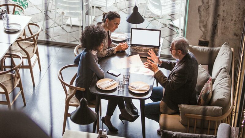 Professionals working at a table in a cafe setting.